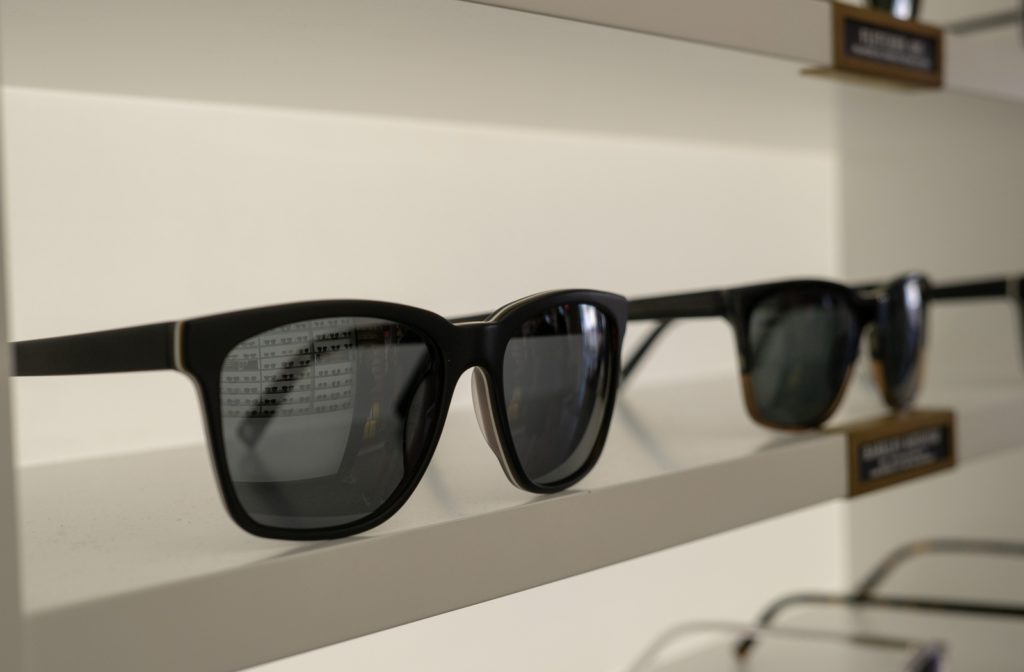 Various prescription sunglasses laid out on a shelf at an optometrist office.